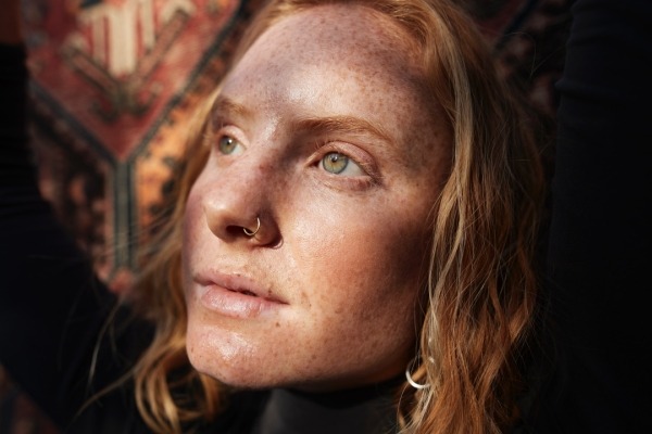 A close-up of a young woman's face looking thoughtfully into the sun's direction.