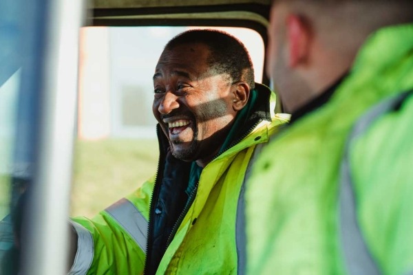 Two road workers sitting in a truck laughing